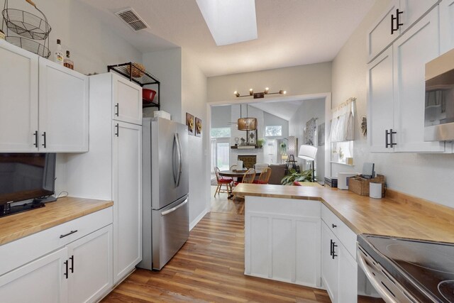 kitchen with visible vents, light wood-type flooring, white cabinets, stainless steel appliances, and butcher block countertops