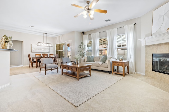 living area with carpet floors, a ceiling fan, baseboards, and a tiled fireplace