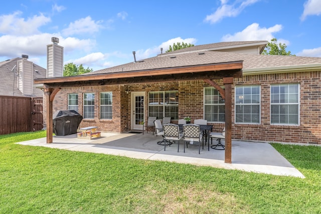 rear view of property with a lawn, brick siding, fence, and a patio