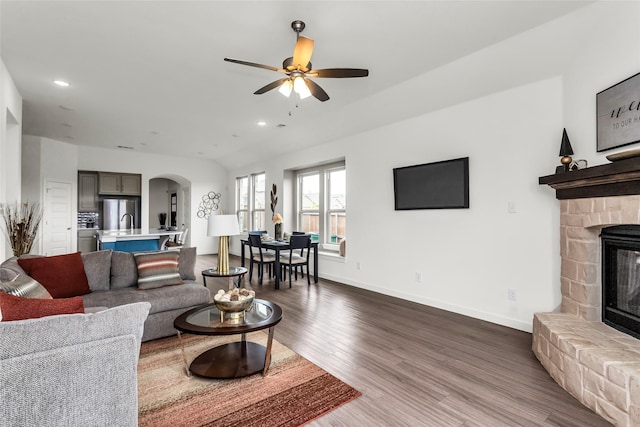 living area with recessed lighting, a ceiling fan, a stone fireplace, and dark wood-type flooring