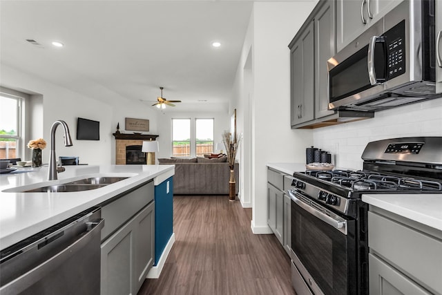 kitchen with stainless steel appliances, a ceiling fan, gray cabinetry, and a sink