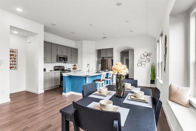 dining area with recessed lighting, arched walkways, baseboards, and dark wood-style flooring
