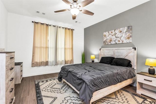 bedroom featuring visible vents, baseboards, ceiling fan, and wood finished floors