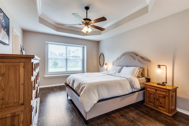 bedroom with ornamental molding, a tray ceiling, and dark wood-style floors