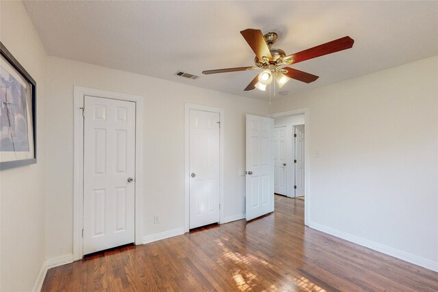unfurnished bedroom featuring baseboards, ceiling fan, wood finished floors, and visible vents