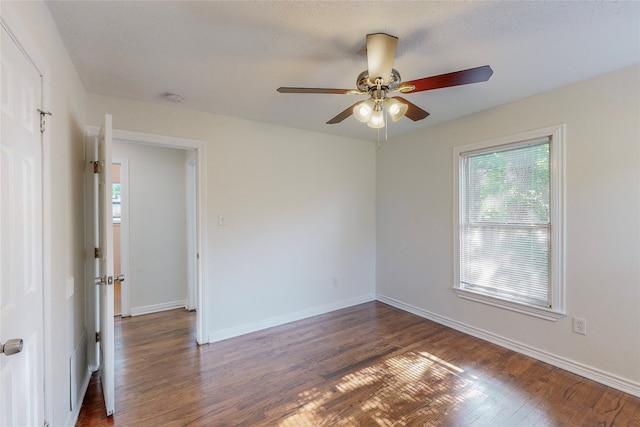 unfurnished room with baseboards, a ceiling fan, and dark wood finished floors