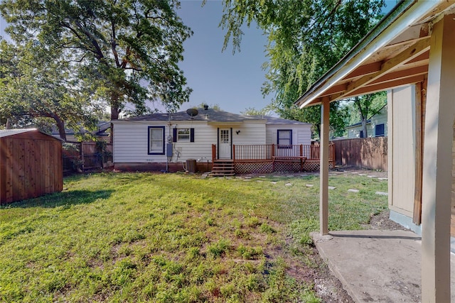 back of house with an outdoor structure, a deck, a fenced backyard, a storage unit, and a lawn