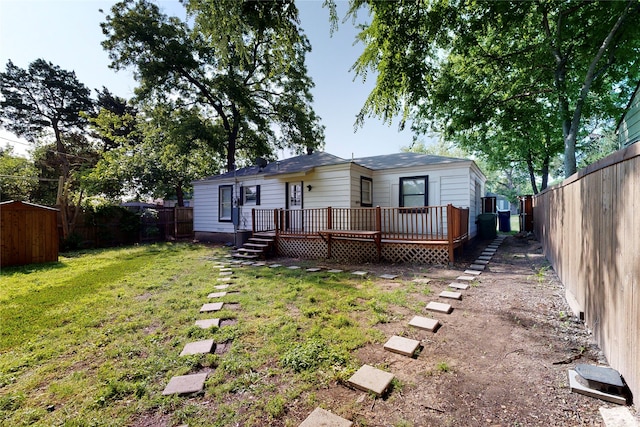 back of house featuring a lawn, a deck, a fenced backyard, and a storage unit