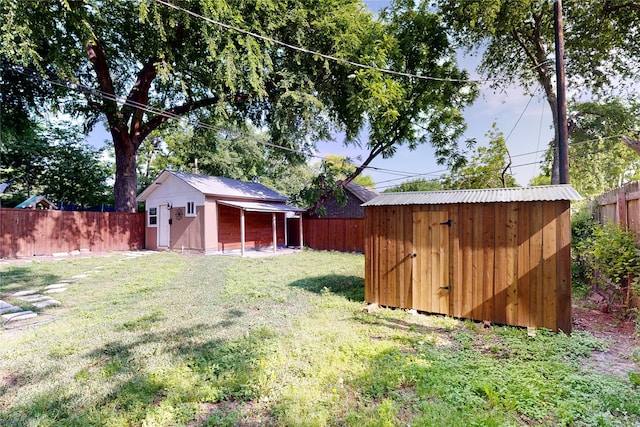 view of yard featuring an outbuilding, a fenced backyard, and a storage unit
