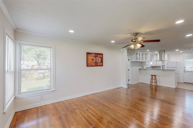 unfurnished living room with ceiling fan, recessed lighting, baseboards, wood finished floors, and ornamental molding