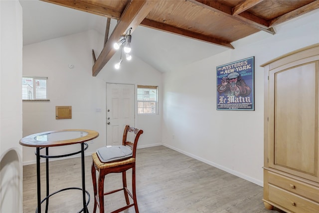 dining room with light wood-type flooring, baseboards, and vaulted ceiling with beams