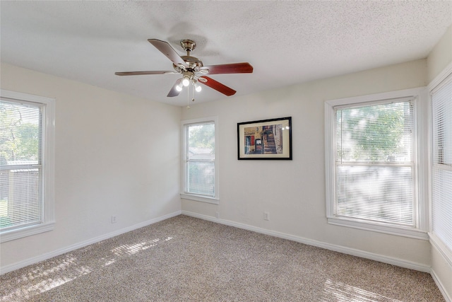 unfurnished room with a ceiling fan, baseboards, light carpet, and a textured ceiling