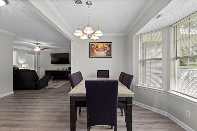 dining space with crown molding, visible vents, wood finished floors, baseboards, and a textured ceiling