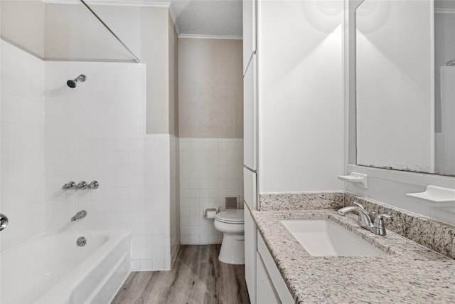 full bathroom with washtub / shower combination, toilet, tile walls, wood finished floors, and ornamental molding
