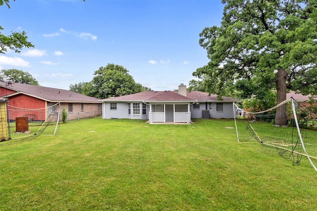 rear view of property featuring a sunroom, fence, a yard, and a chimney
