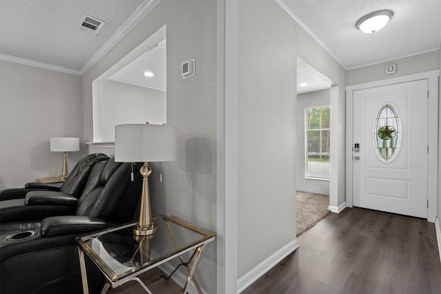 foyer featuring a textured ceiling, visible vents, dark wood finished floors, baseboards, and ornamental molding