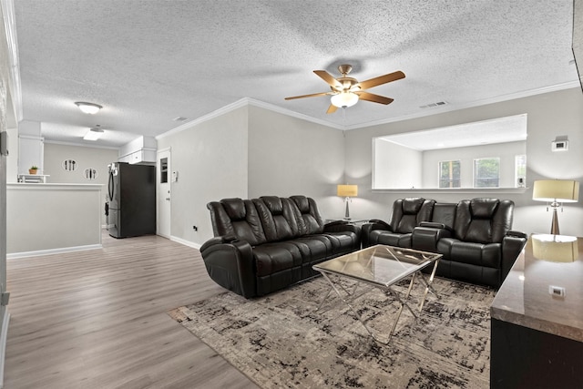 living area featuring a ceiling fan, a textured ceiling, visible vents, crown molding, and light wood-style flooring