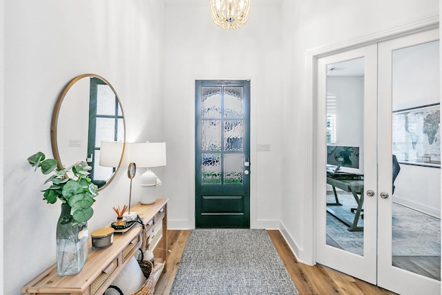 foyer with baseboards, french doors, a notable chandelier, and wood finished floors