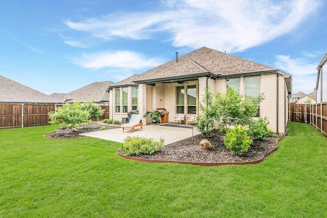 back of house featuring roof with shingles, brick siding, a fenced backyard, a patio area, and a lawn