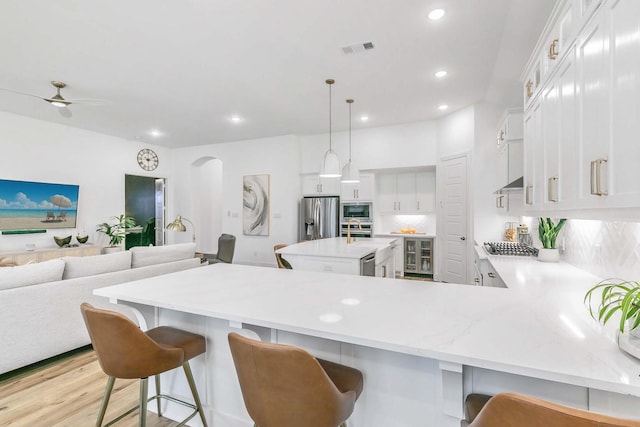 kitchen with visible vents, decorative backsplash, wine cooler, light countertops, and appliances with stainless steel finishes