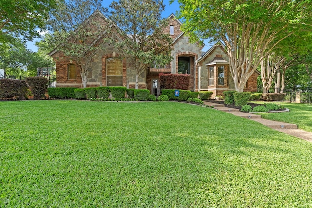 tudor house featuring a front lawn and stone siding