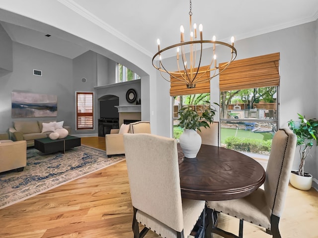 dining room with visible vents, wood finished floors, a notable chandelier, and a wealth of natural light