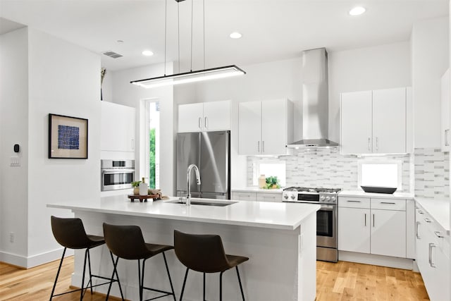 1944 Kearney Ct, Dallas, TX 75204 - kitchen featuring a sink, light wood-style flooring, wall chimney exhaust hood, stainless steel appliances, and visible vents