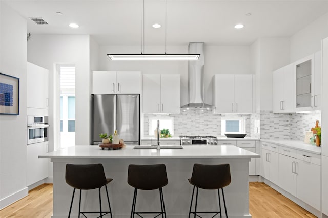 1944 Kearney Ct, Dallas, TX 75204 - kitchen featuring a breakfast bar area, stainless steel appliances, a sink, and wall chimney exhaust hood