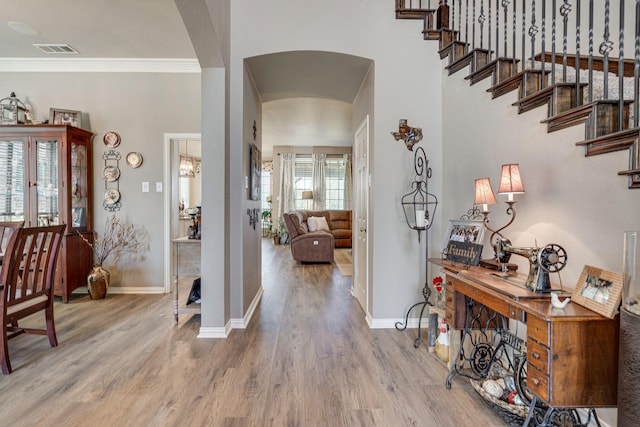 foyer entrance with visible vents, arched walkways, baseboards, and wood finished floors