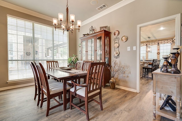 dining area with plenty of natural light, visible vents, baseboards, a chandelier, and ornamental molding