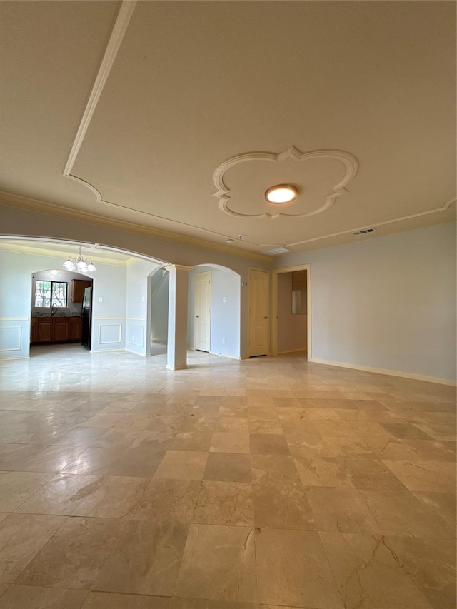 unfurnished room featuring crown molding, a sink, arched walkways, baseboards, and visible vents