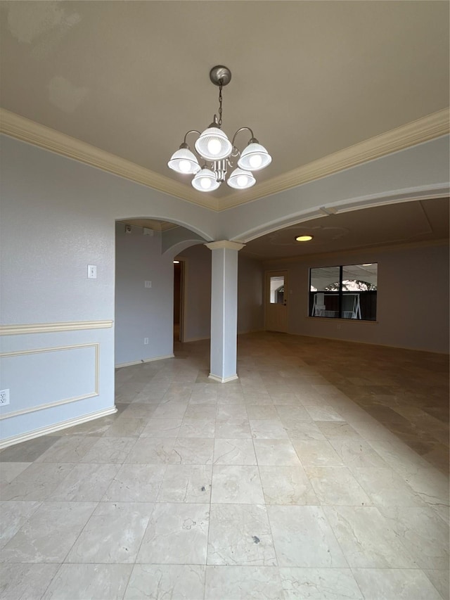 unfurnished dining area featuring crown molding, arched walkways, ornate columns, and a chandelier