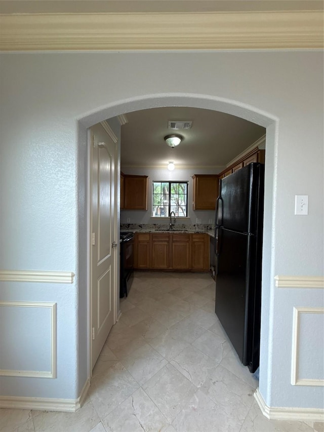 kitchen with a sink, arched walkways, baseboards, visible vents, and black appliances