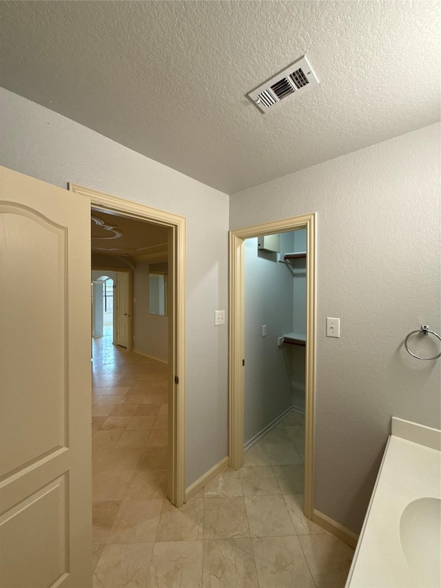 bathroom featuring baseboards, a textured ceiling, and visible vents