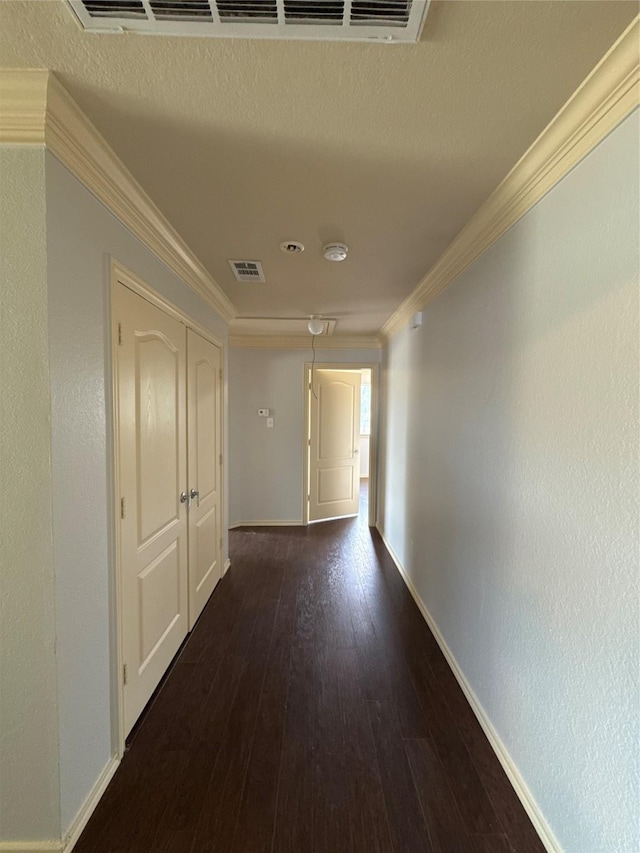 hall with baseboards, ornamental molding, visible vents, and hardwood / wood-style floors