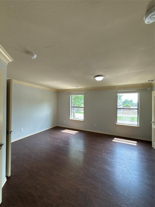 spare room featuring crown molding, baseboards, a textured ceiling, and dark wood-type flooring