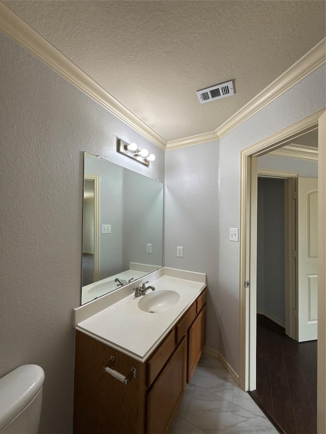 half bathroom with crown molding, vanity, toilet, marble finish floor, and visible vents