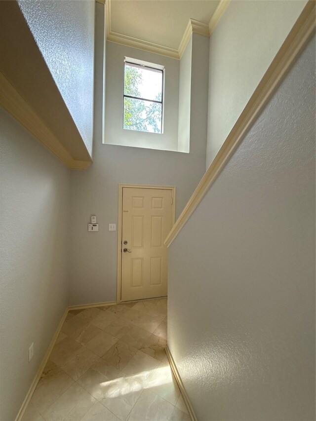 foyer entrance with crown molding and baseboards