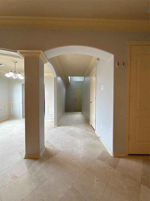 hallway with arched walkways, a decorative wall, a chandelier, and ornamental molding