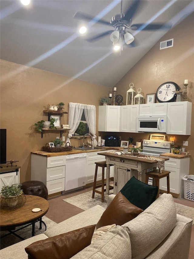 kitchen with visible vents, a sink, white appliances, white cabinets, and a ceiling fan