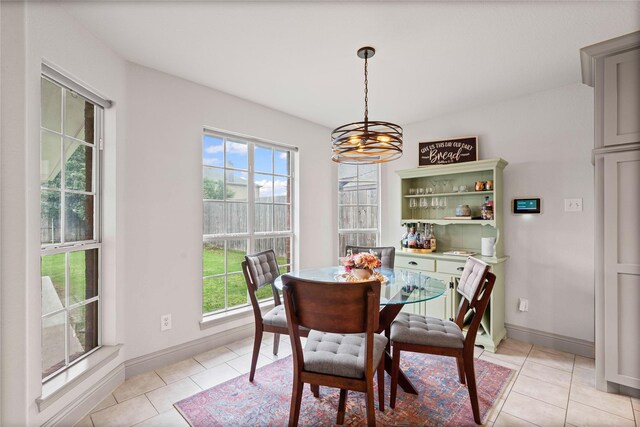 dining space featuring baseboards, light tile patterned floors, a notable chandelier, and a wealth of natural light
