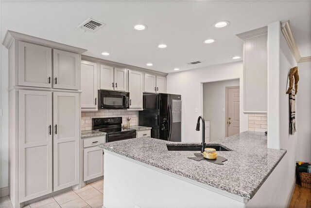 kitchen with visible vents, a sink, a peninsula, and black appliances