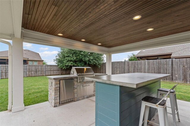 view of patio featuring a fenced backyard, outdoor dry bar, exterior kitchen, and grilling area