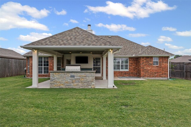 rear view of property featuring brick siding, area for grilling, a fenced backyard, a lawn, and a patio