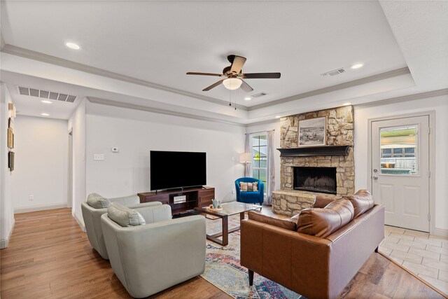 living room with visible vents, a stone fireplace, ceiling fan, light wood-type flooring, and a raised ceiling