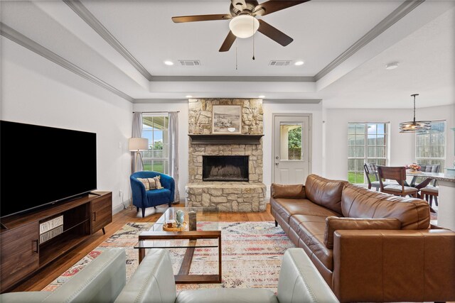 living area with a raised ceiling, wood finished floors, and visible vents