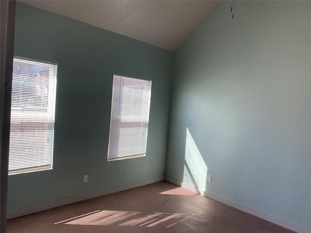 spare room featuring baseboards and vaulted ceiling