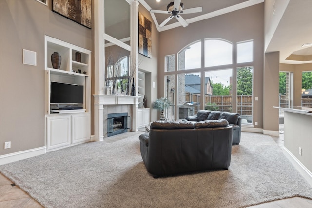 living area with ceiling fan, crown molding, built in shelves, baseboards, and carpet flooring