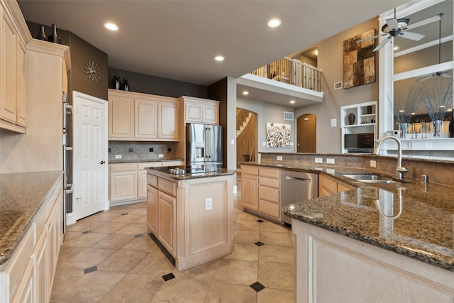 kitchen featuring decorative backsplash, a ceiling fan, light brown cabinetry, a sink, and stainless steel appliances