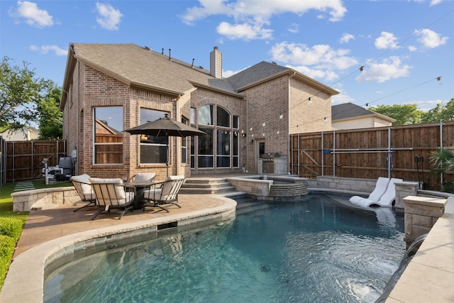 view of swimming pool featuring a pool with connected hot tub, a fenced backyard, a patio area, and a grill